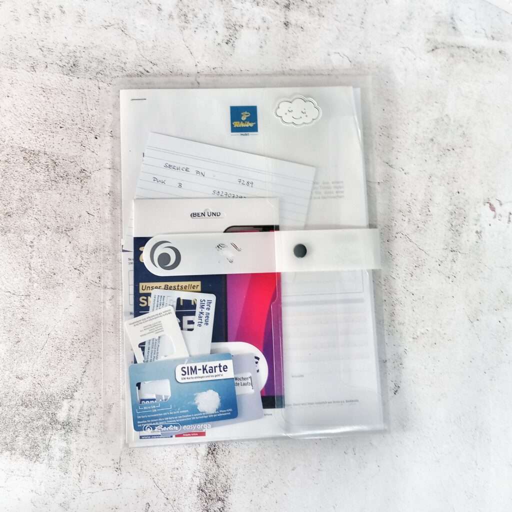 Klarsichthülle mit SIM-Karten und Unterlagen zu Mobilfunkverträgen, verschließbar mit einem Druckknopf